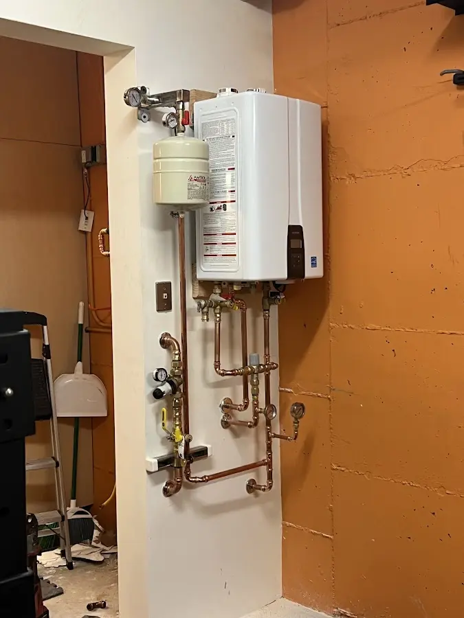 Plumbing technician inspecting water heater connections in Watervliet
